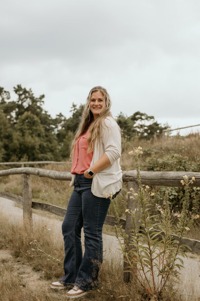 Eva Kuijken poseert buiten bij houten hek in grasland.